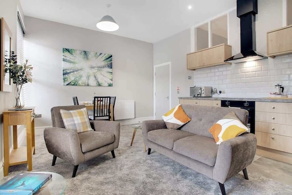A modern living room with a sofa, armchairs, a coffee table, and a dining area with a chair and table.