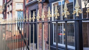 A metal fence with pointed tops and decorative elements, likely part of a building's exterior.
