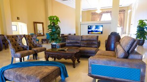 A spacious lobby with a large seating area, including a sofa set and armchairs, a coffee table, and two potted plants. - URBAN LIFESTYLES HOTEL (Masvingo)
