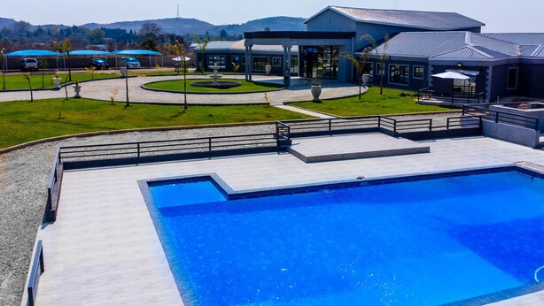 A modern building with a swimming pool, a covered patio, and a landscaped garden. - URBAN LIFESTYLES HOTEL (Masvingo)