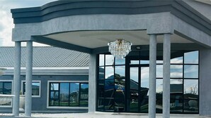 A modern building with a covered entrance, large windows, and a central chandelier. - URBAN LIFESTYLES HOTEL (Masvingo)