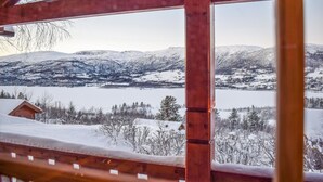 Una cabaña de madera con vistas a un lago nevado y montañas.