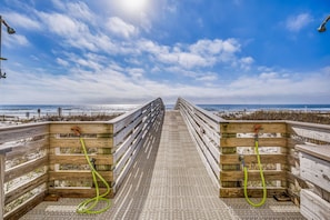 Una passerella di legno che conduce alla spiaggia, con cielo sereno.