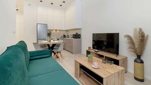 Un salon moderne avec un canapé vert, une table basse en bois et un meuble pour la télévision.