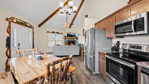 A kitchen with wooden cabinets, stainless steel appliances, and a dining area with a wooden table and chairs.