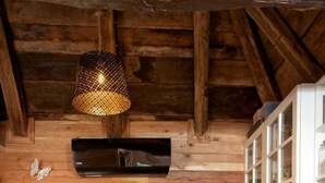 Une cuisine rustique aux murs en bois, dotée d’une hotte noire, d’un meuble blanc aux portes en verre et d’une petite étagère où sont posées des bouteilles.