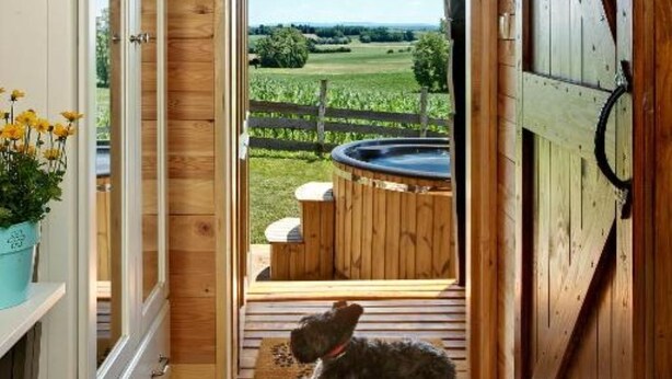 Un intérieur en bois, avec un chien allongé sur le sol, un jacuzzi à l’extérieur et une pancarte indiquant « Route 66 ».