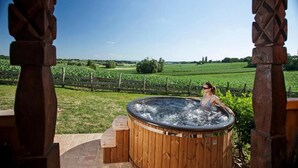Un bain à remous installé à l’extérieur, avec un vignoble en arrière-plan.