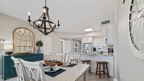 A modern kitchen with white cabinets, a central island, and a chandelier. - Tidewater 102- Orange Beach - 2bd/2bath - Beachfront (Orange Beach)