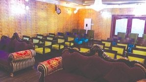 A room with rows of chairs and sofas, a clock on the wall, and a door with glass panels. - The Royal Suite (Bhubaneshwar)