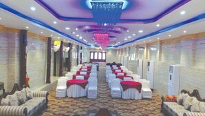 A banquet hall with rows of tables, white chairs, and a central aisle. - The Royal Suite (Bhubaneshwar)