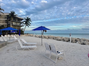 Relax on the beach with comfortable lounge chairs and umbrellas, surrounded by a natural barrier of rocks.