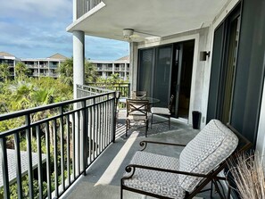 Enjoy the view from this balcony with a table and two chairs.