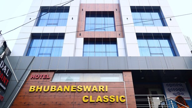 Een hotel genaamd "BHUBANESWARI CLASSIC" met een moderne gevel, grote ramen en een duidelijke entree.