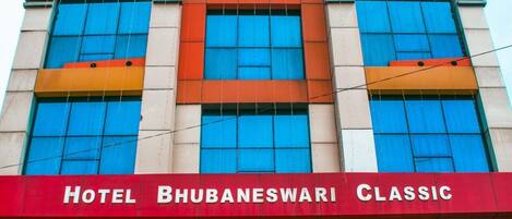 A hotel facade with large windows and a sign reading "HOTEL BHUBANESWARI CLASSIC".