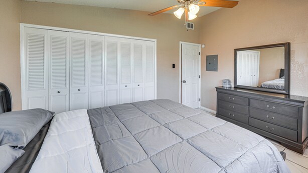 A bedroom with a large bed, a dresser, a mirror, and a ceiling fan. - San Antonio Home Near AFB & Hospitals: WFH Welcome (San Antonio)