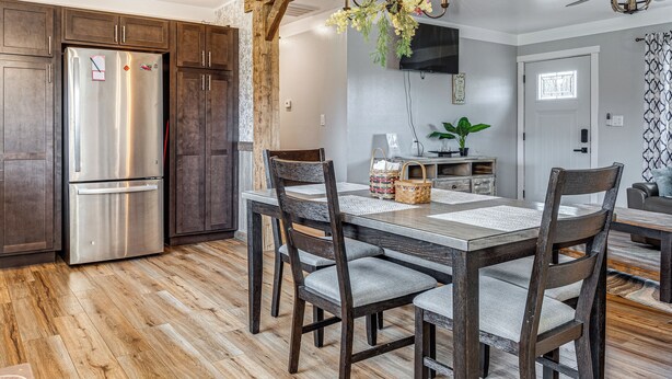 Een moderne keuken met een koelkast van roestvrij staal, houten kastjes, een eettafel met stoelen en een kroonluchter.