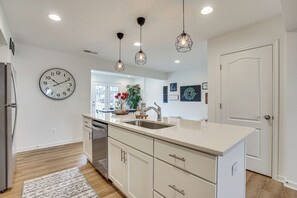 Una cocina moderna con una isla grande, electrodomésticos de acero inoxidable, iluminación colgante y vistas al comedor.
