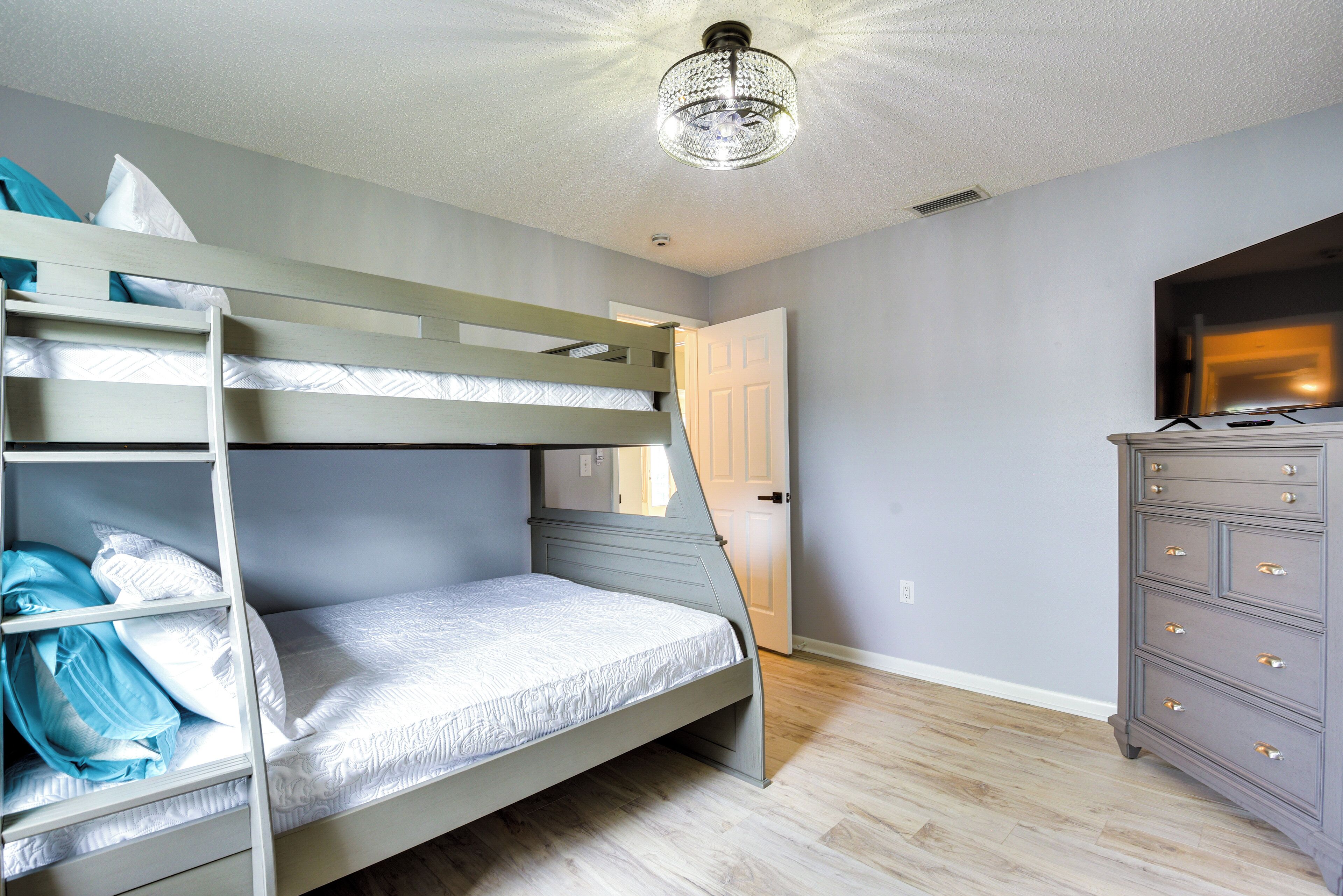 Een stapelbed met een ladder, een dressoir en een televisie aan de muur.