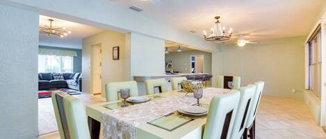 A dining area with a table set for six, a ceiling fan, and a chandelier.
