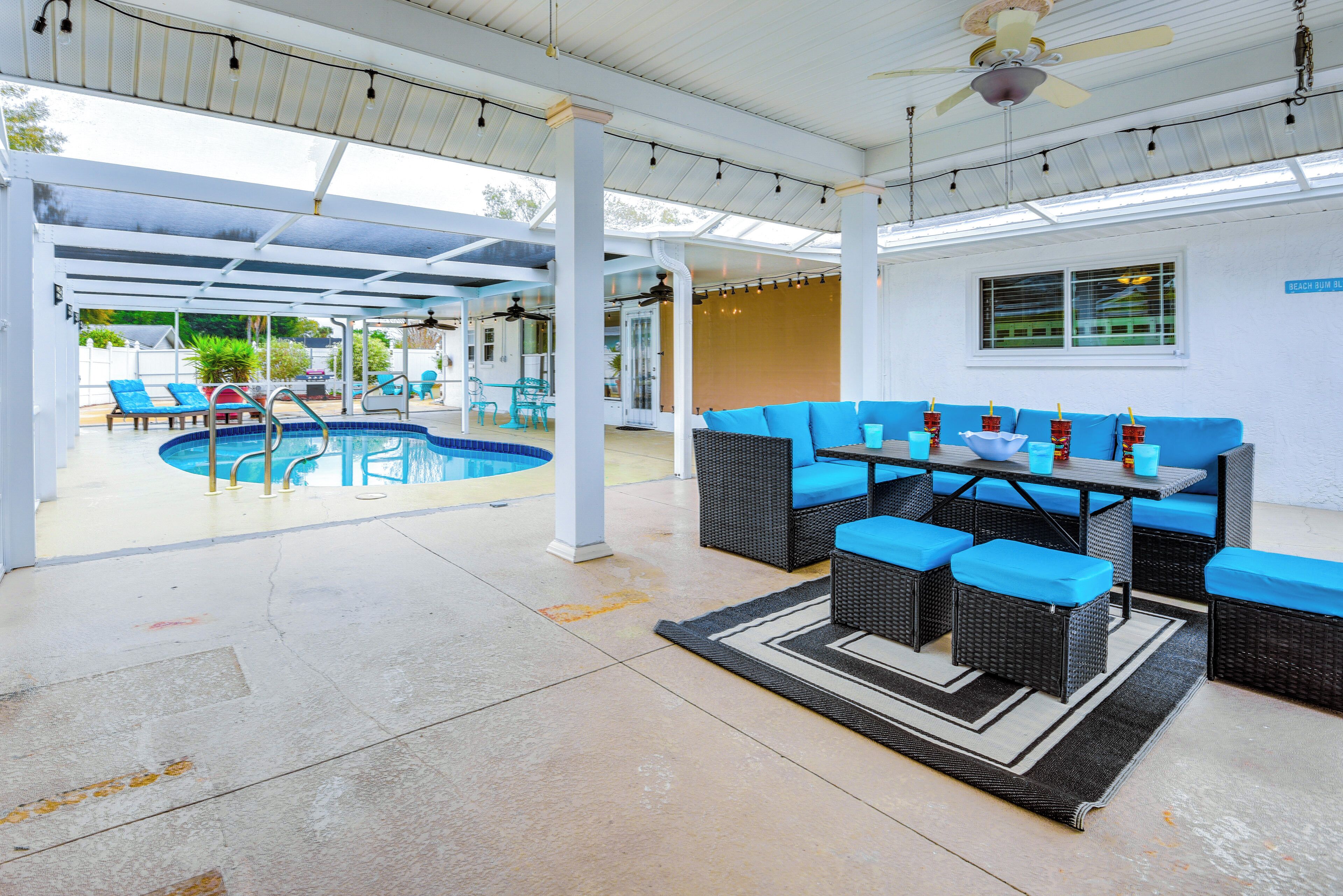 A covered outdoor area with a pool, seating, and a ceiling fan.