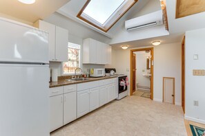 A modern kitchen with white cabinets, a microwave, a stove, and a skylight. - Charming Old Lyme Cottage, Steps to Private Beach! (Old Lyme)