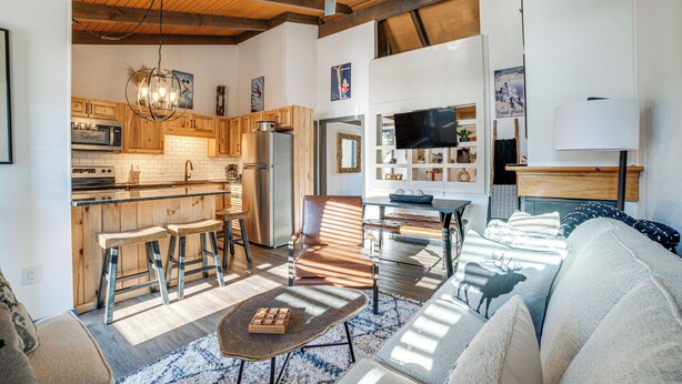 A modern kitchen with wooden cabinets, a built-in microwave, and a large island with stools. - Chic Greek Peak Ski Resort Townhome w/ Balconies! (Cortland)