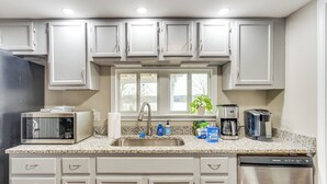 A kitchen with white cabinets, a stainless steel sink, a microwave, a coffee maker, and a dishwasher. - Lakefront Getaway w/ Porch in Athens Area! (Statham)