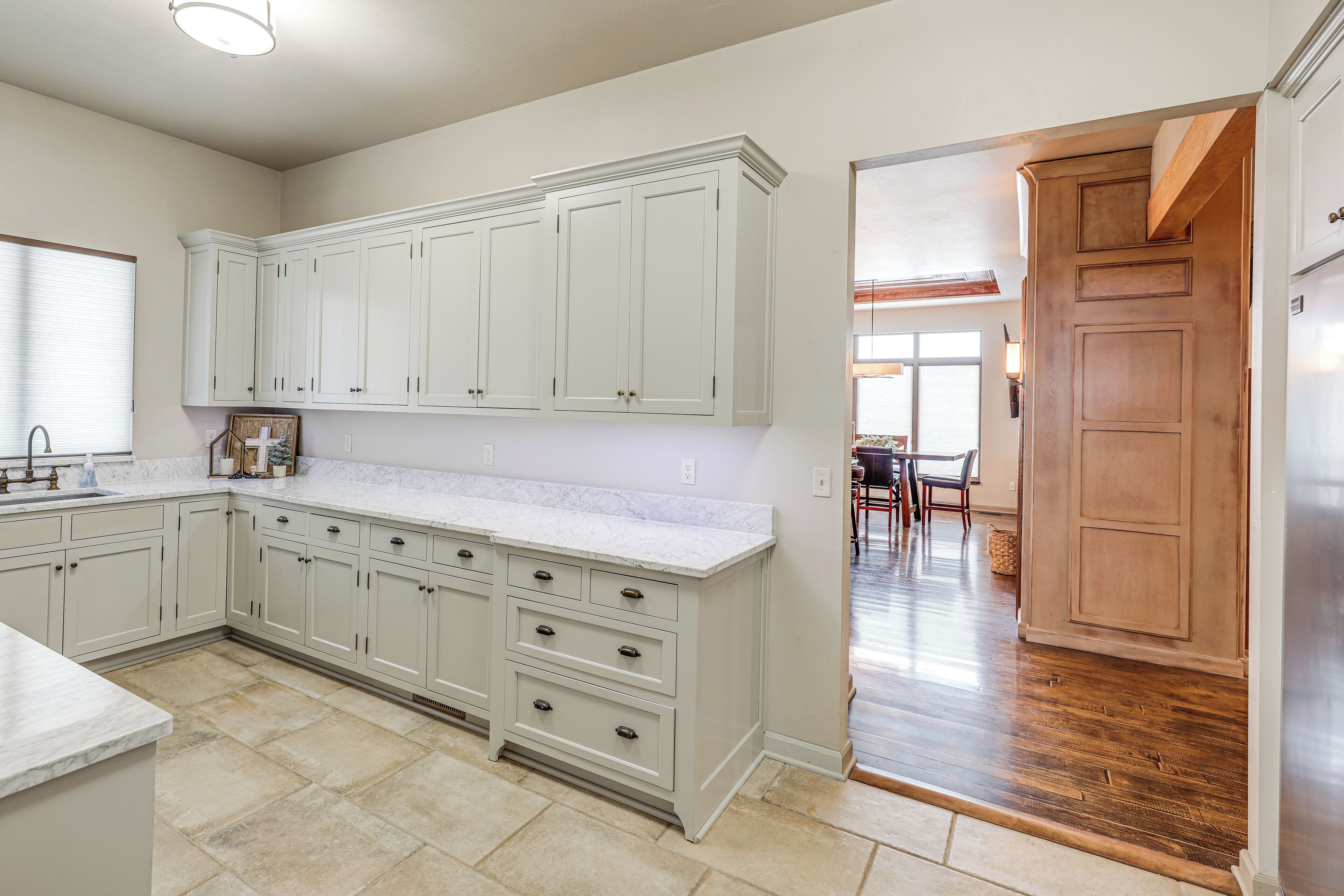 A kitchen with white cabinetry, a marble countertop, and a wooden floor.