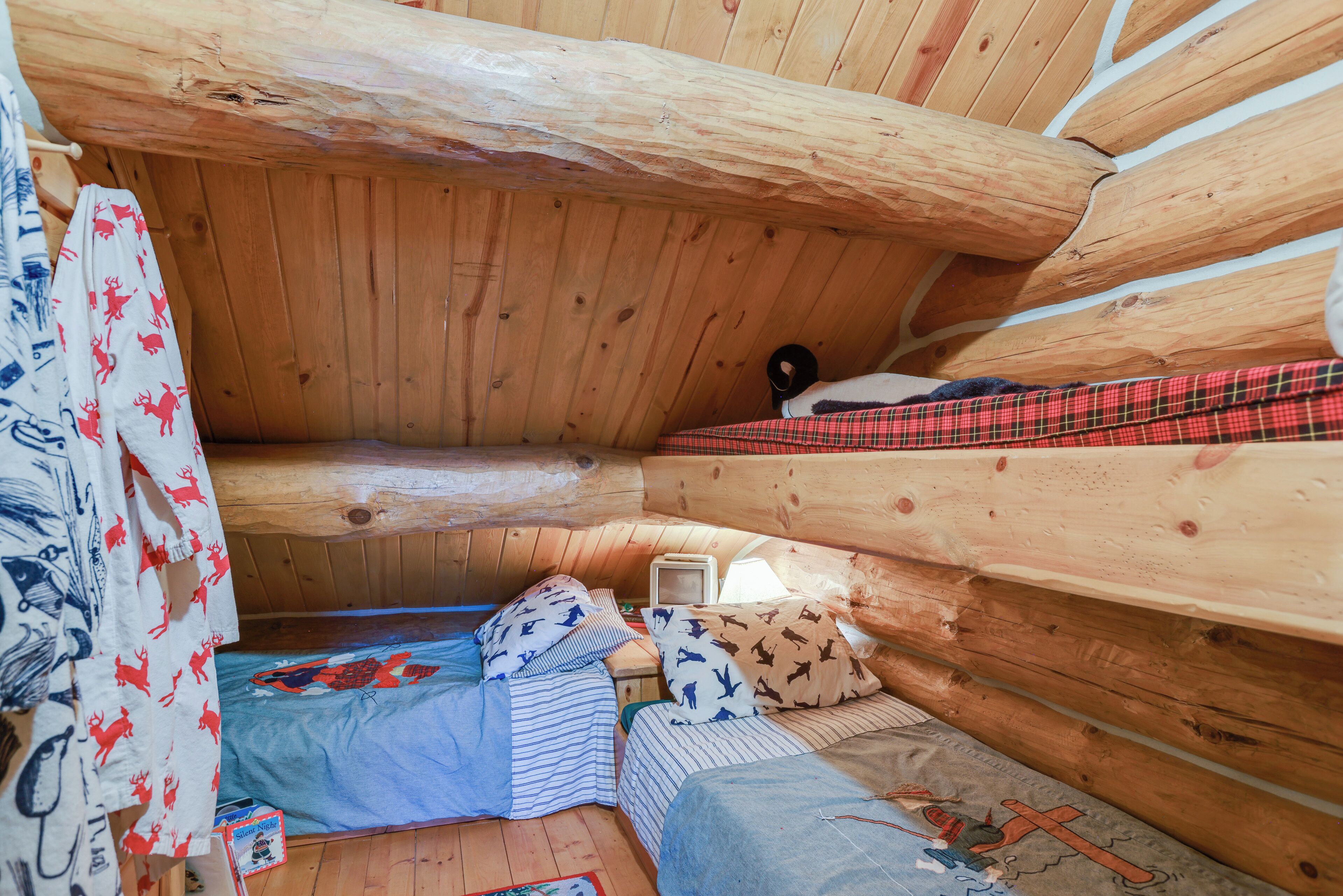 A cozy cabin with a sloped ceiling, wooden walls, and a bed with patterned bedding.