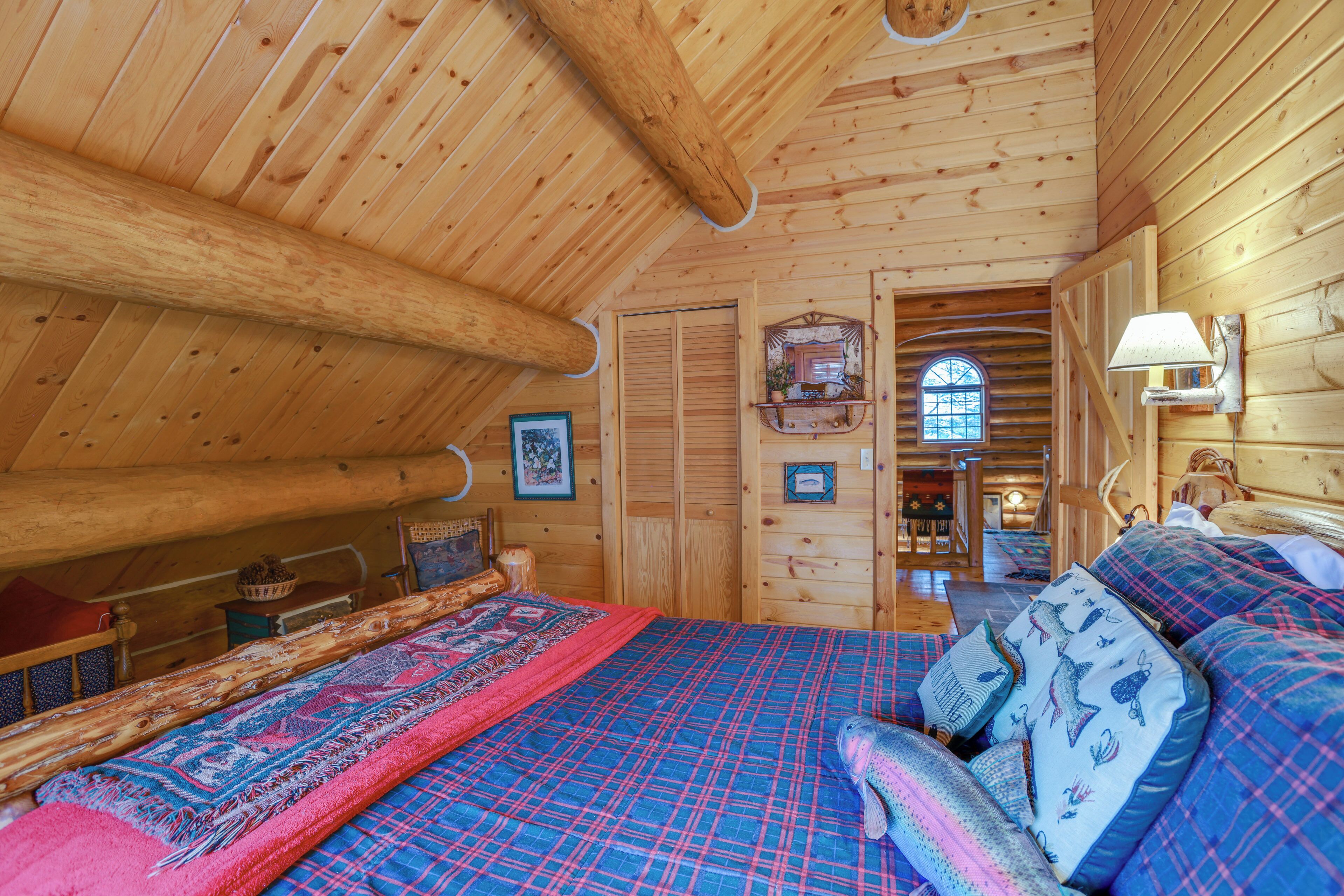 Ein gemütliches Schlafzimmer in einer Blockhütte mit einem großen Bett, einer Holzbalkendecke und einem kleinen Fenster.