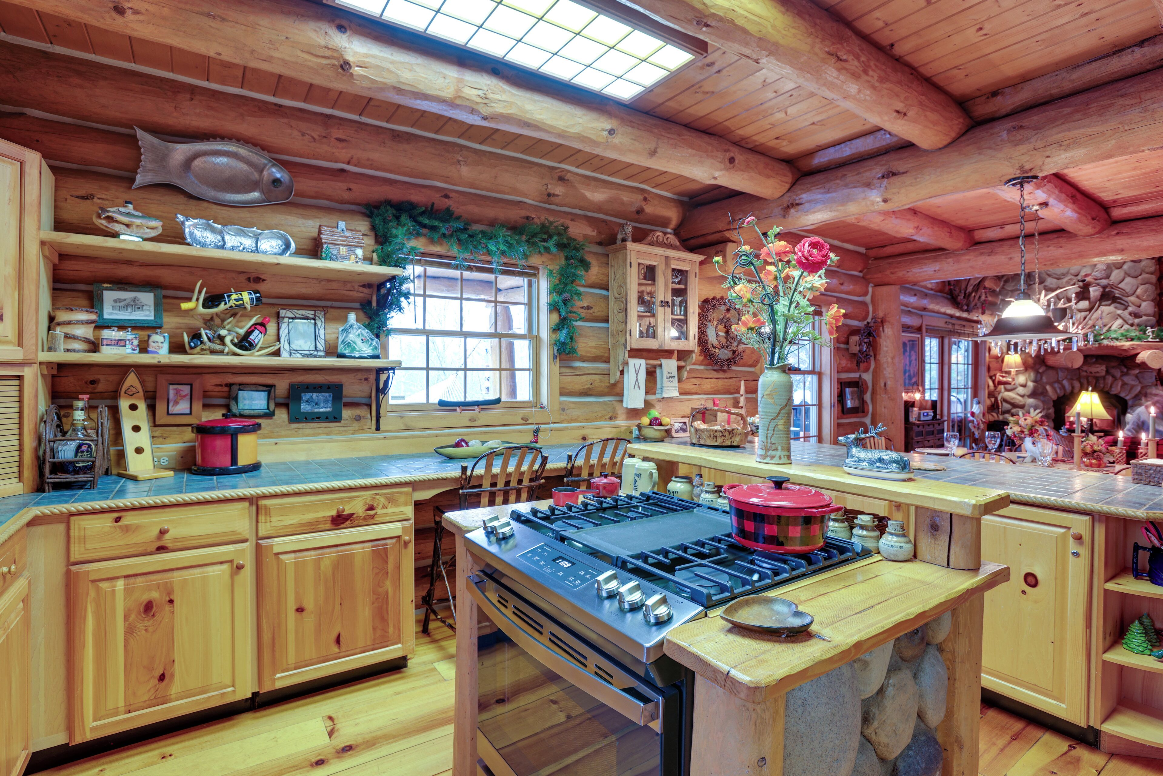 A rustic kitchen with wooden cabinets, a large stove, and a window with a wreath.