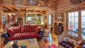 L’intérieur d’un chalet confortable, avec un canapé à carreaux rouges et noirs, des fauteuils en osier et une table à manger en bois.