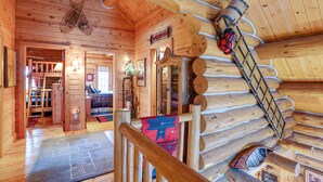L’intérieur d’une cabane en rondins, avec un escalier en bois, un sapin de Noël et une cheminée chaleureuse.