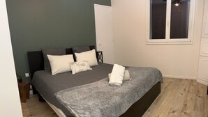 Un dormitorio con cama, ventana y suelo de madera.