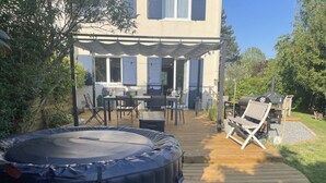 Una terraza de madera con mobiliario exterior, un jacuzzi y un porche cubierto.