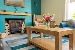 Een gezellige woonkamer met een open haard, een houten salontafel en een bank.