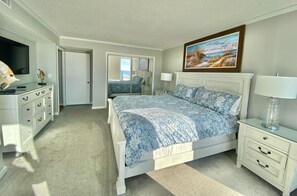 Un dormitorio con cama, cómoda, televisor y un cuadro en la pared.