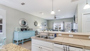 A kitchen with a granite countertop, white cabinets, a blue dresser, and a ceiling fan. - Made In The Shade Rp808 3 Bedroom Home by RedAwning (Rockport)