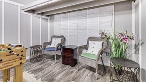A room with two wicker chairs, a small wooden table, and a tall potted plant. - Made In The Shade Rp808 3 Bedroom Home by RedAwning (Rockport)