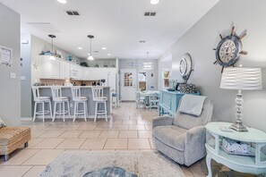 A modern kitchen with white cabinets, a dining area with a table and chairs, and a living room with a sofa and a lamp. - Made In The Shade Rp808 3 Bedroom Home by RedAwning (Rockport)