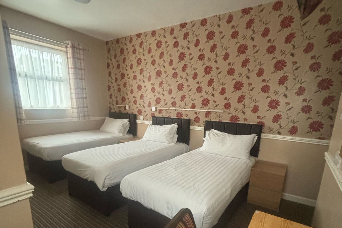 A hotel room with two single beds, a wooden desk, and a chair.