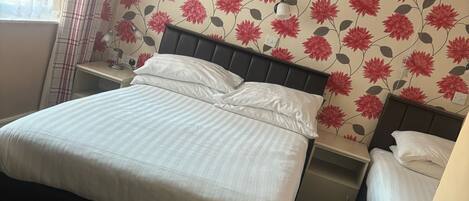 Et hotelværelse med seng, sengeborde, lampe og radiator.
