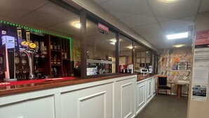 A bar area with a counter, shelves with bottles, and a sign indicating a price limit. - The Beechfield Hotel (Blackpool)
