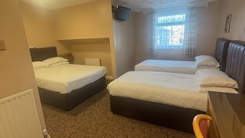 Quarto de hotel com duas camas, televisão, janela com cortinas e carpete estampado.