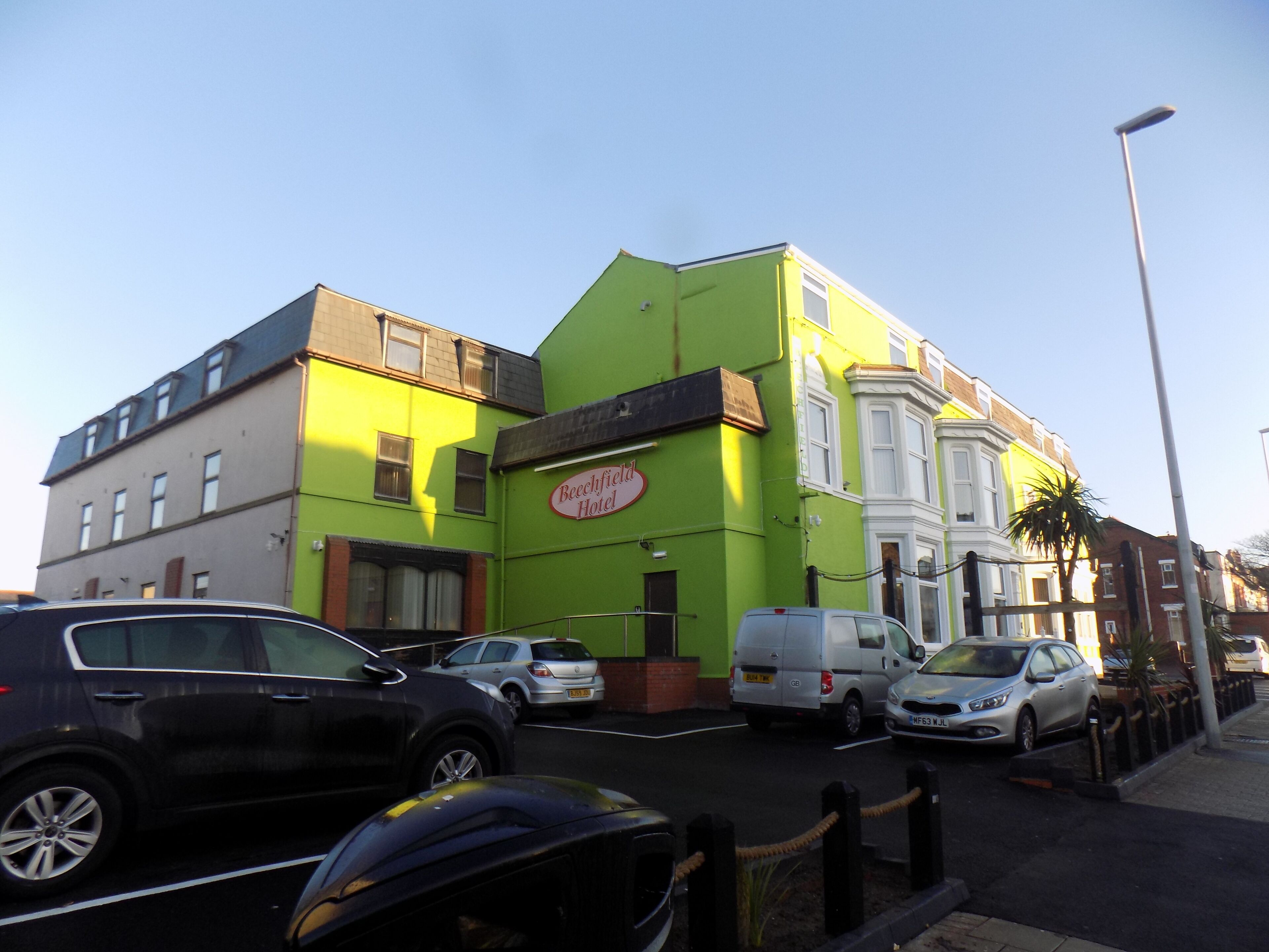A hotel with a green facade and a sign reading "Beechfield Hotel."