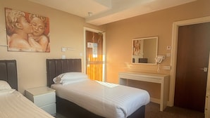 A hotel room with two beds, a desk, a mirror, and a painting on the wall. - The Beechfield Hotel (Blackpool)