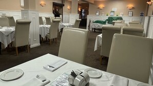 A dining area with tables set for service, featuring white tablecloths and plates. - The Beechfield Hotel (Blackpool)