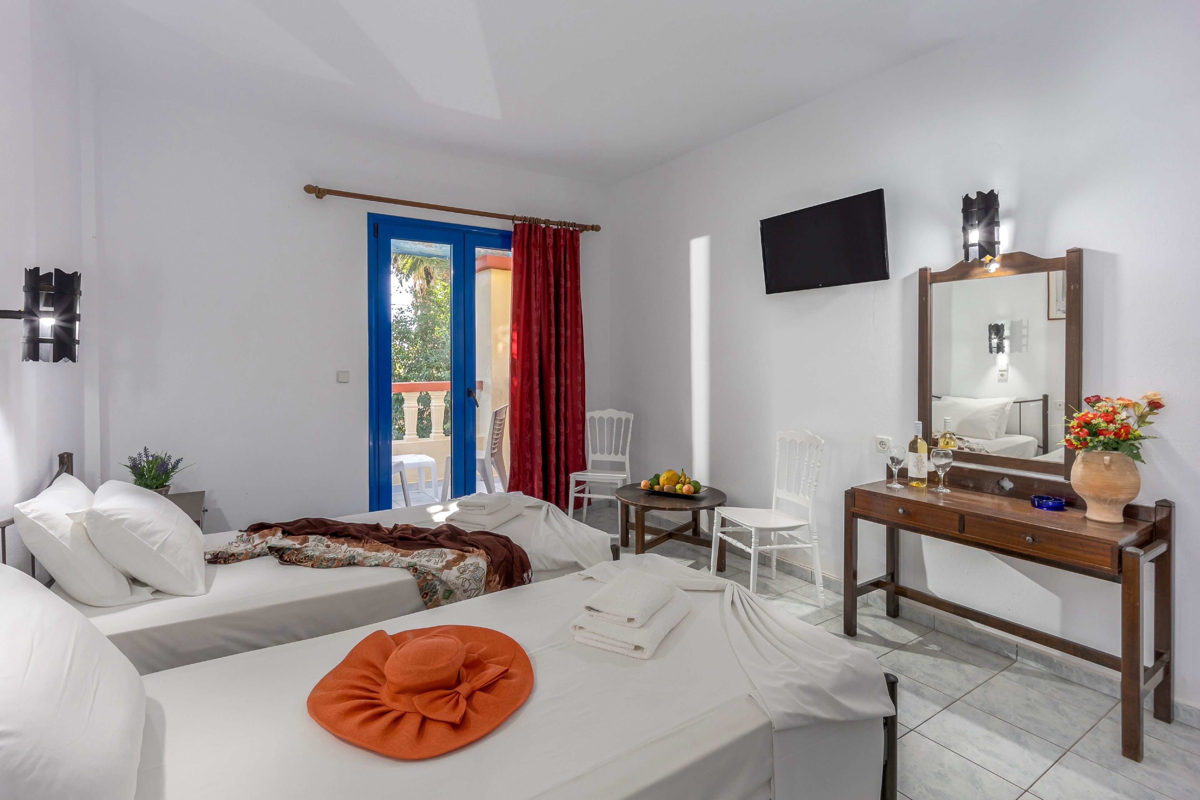 A hotel room with a bed, a desk, a chair, a TV, and a window with curtains.