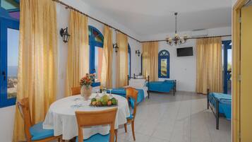 Una habitación con una mesa de comedor, sillas, una cama y un televisor.